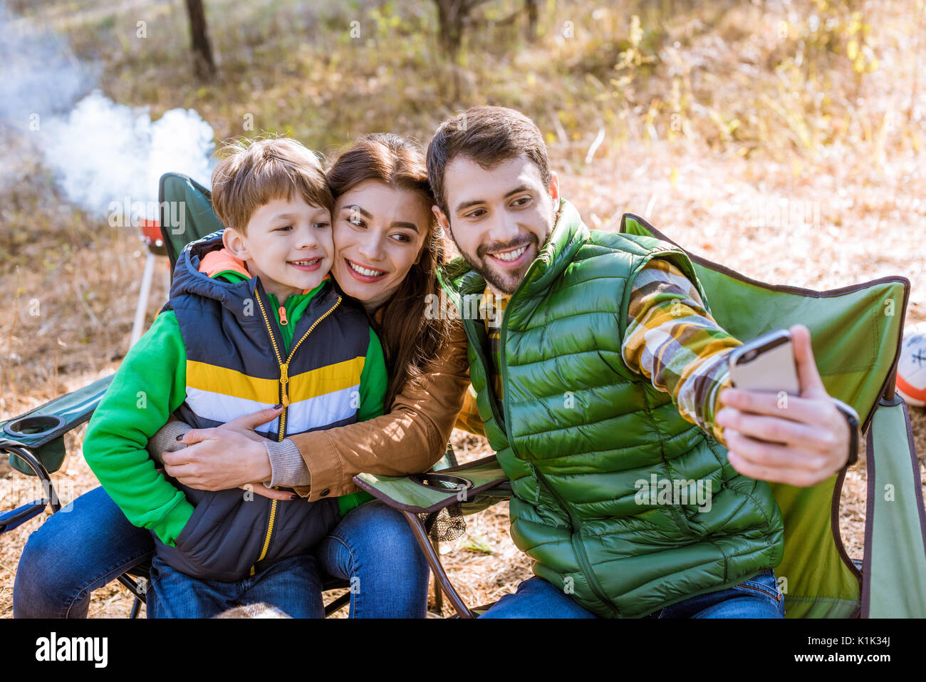 Sorridenti famiglia al picnic a divertirsi e tenendo selfie in autunno park Foto Stock