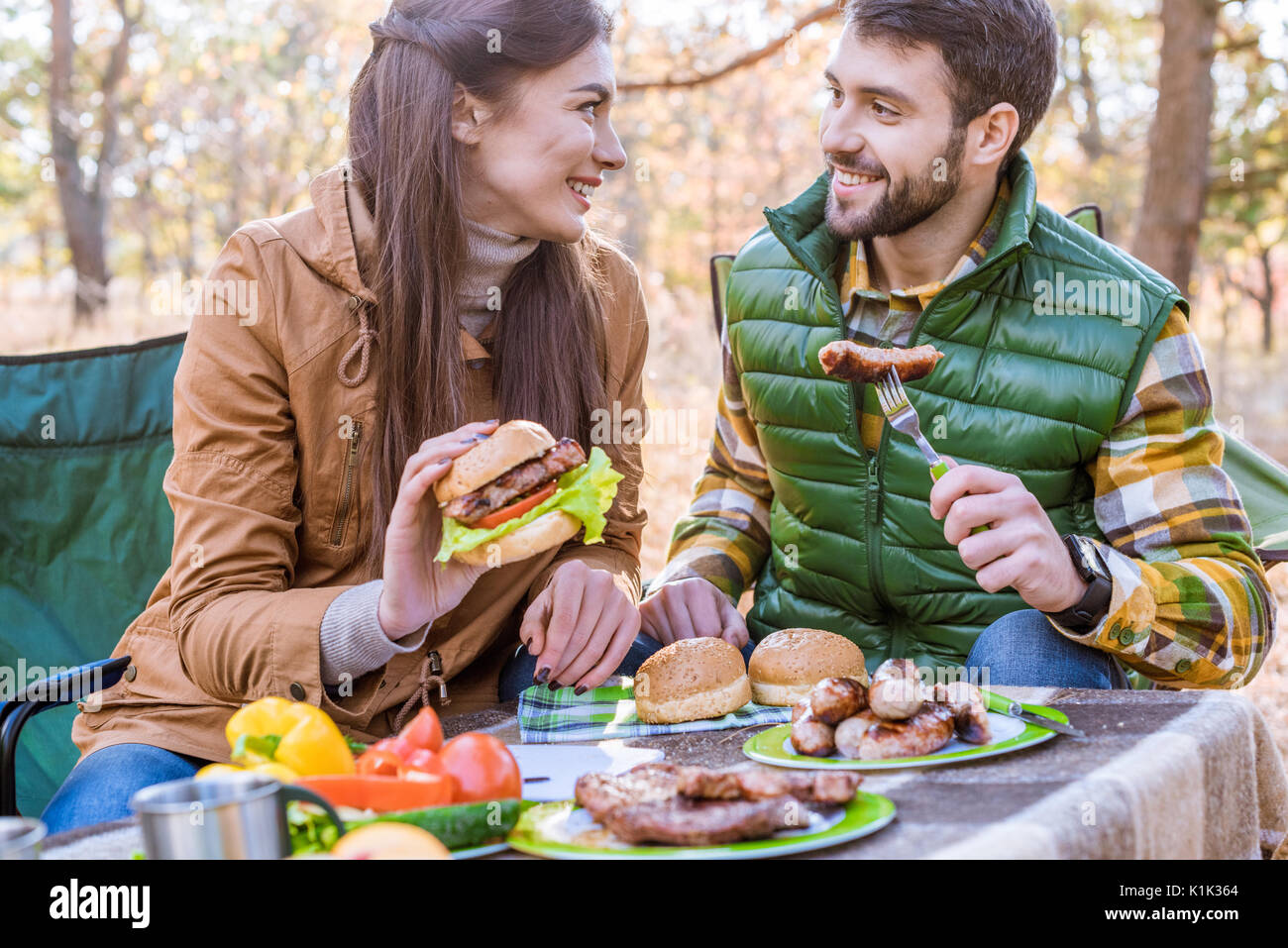 Close-up ritratto di sorridenti coppia giovane seduto a tavola e mangiare il picnic nella foresta di autunno Foto Stock
