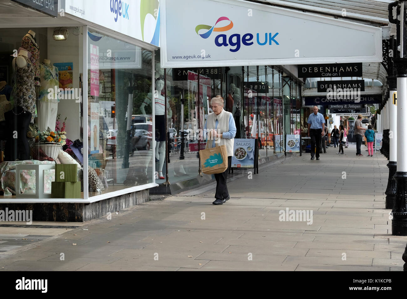 Signora anziana oltrepassando età UK shop a Southport Foto Stock