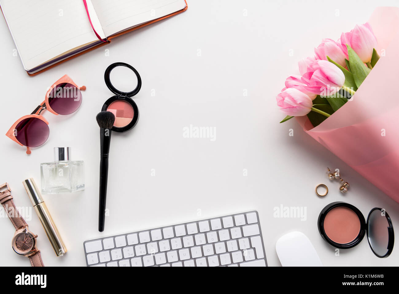 Lay piatto con vari cosmetici, accessori e bouquet di tulipani rosa isolato su bianco Foto Stock