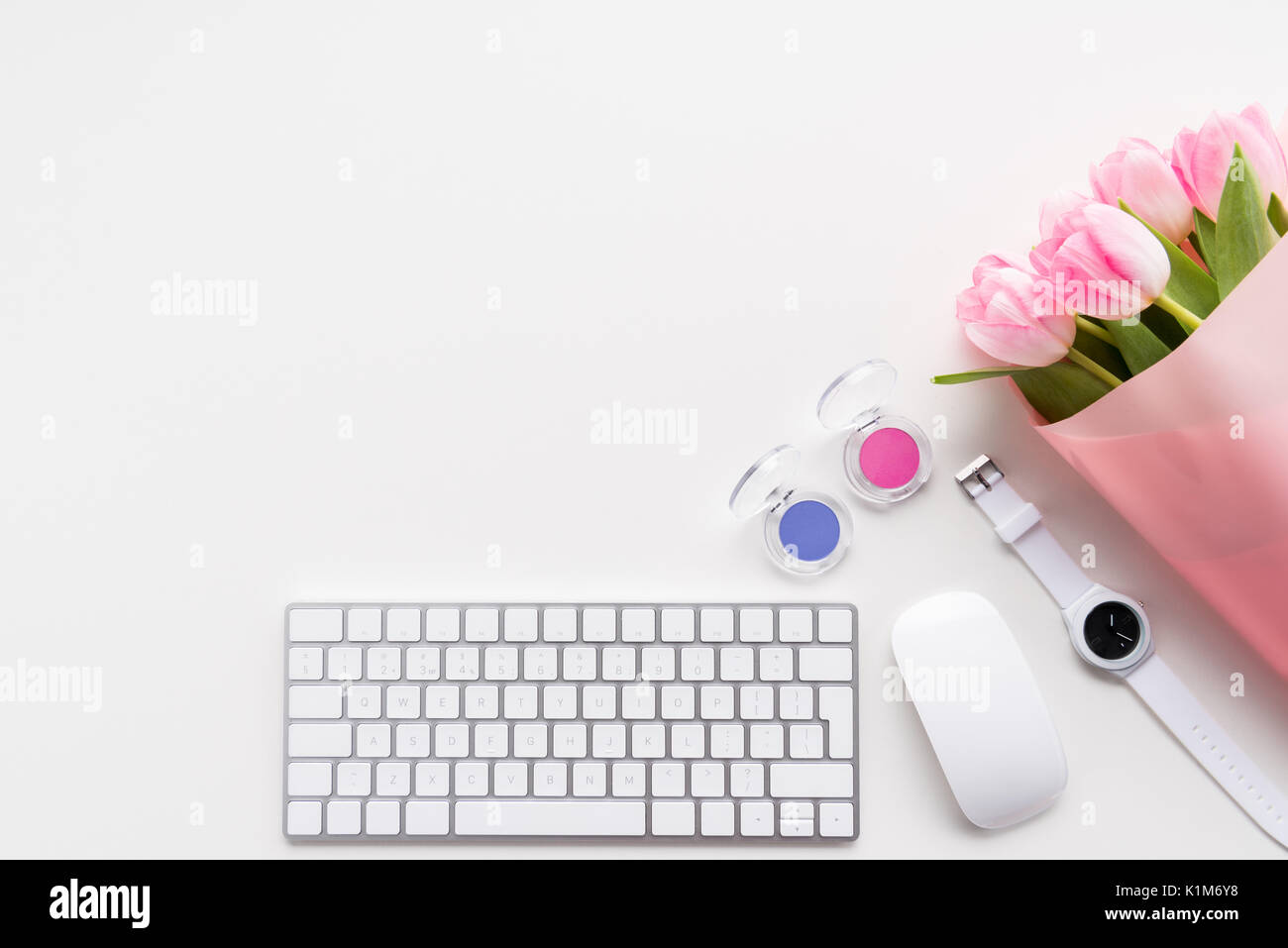 Piatto di laici bel bouquet di tulipani rosa, la tastiera e il mouse del computer isolato su bianco Foto Stock