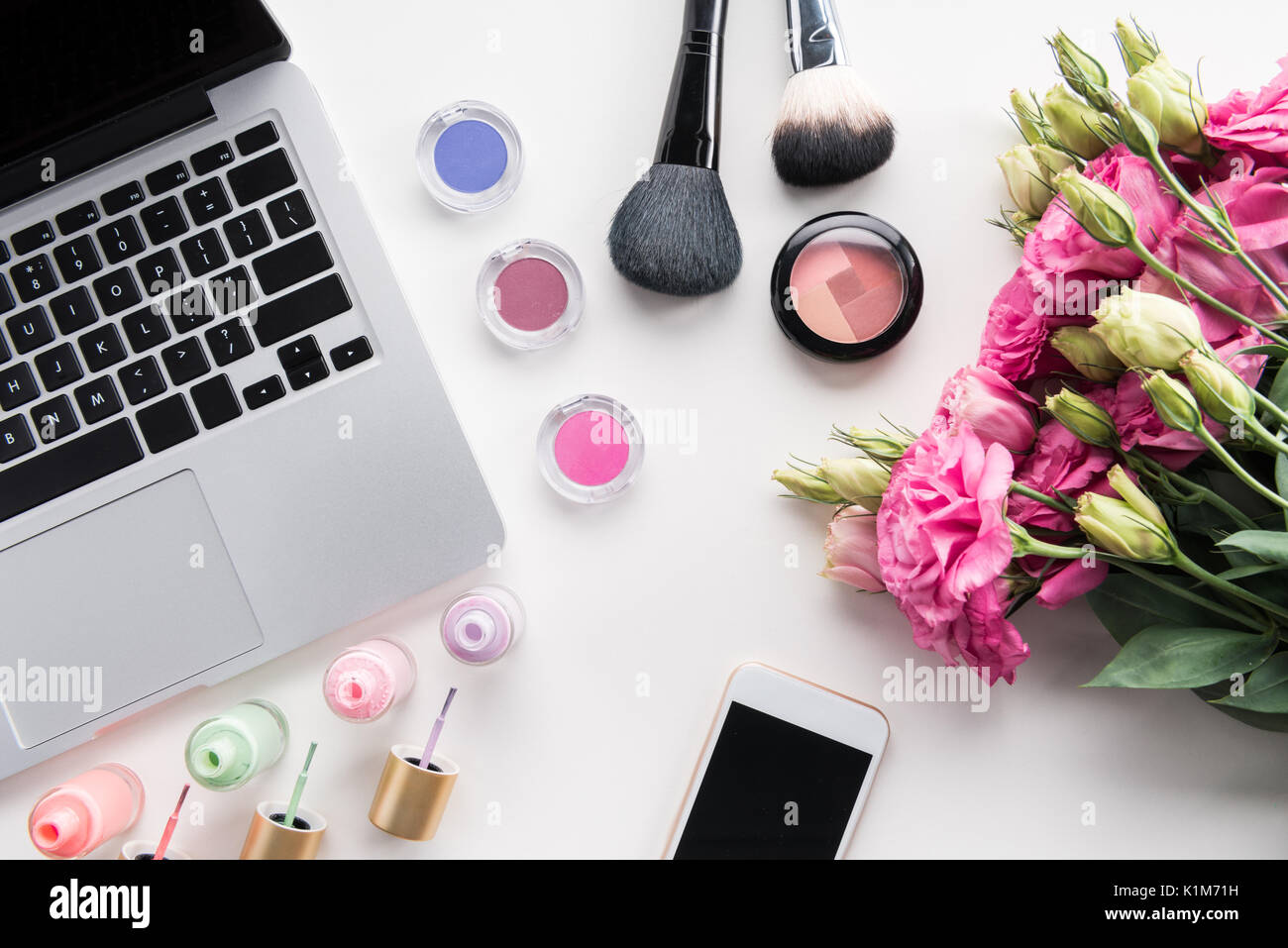 Lay piatto con vari cosmetici, bouquet di fiori, portatile e lo smartphone isolato su bianco Foto Stock