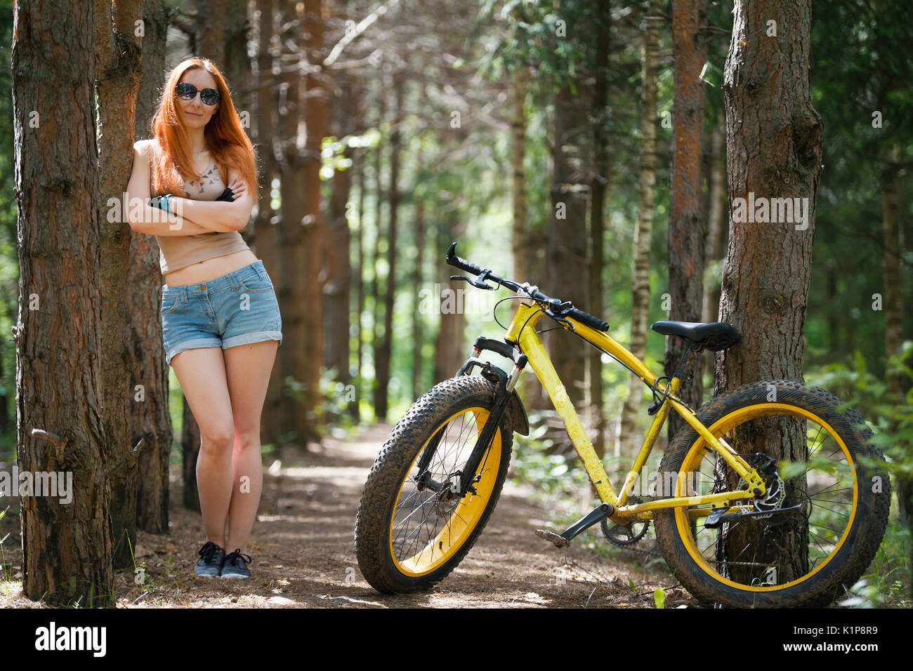 I Capelli rossi ragazza in pantaloncini corti sorge accanto al giallo  bicicletta fatbike Foto stock - Alamy
