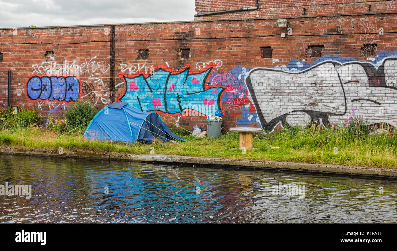 Fotografia di una piccola tenda piantato da un canale che indica un impatto sociale e che mostra il modo in cui l'occupante è vivere in modo irregolare a un centro della città Foto Stock