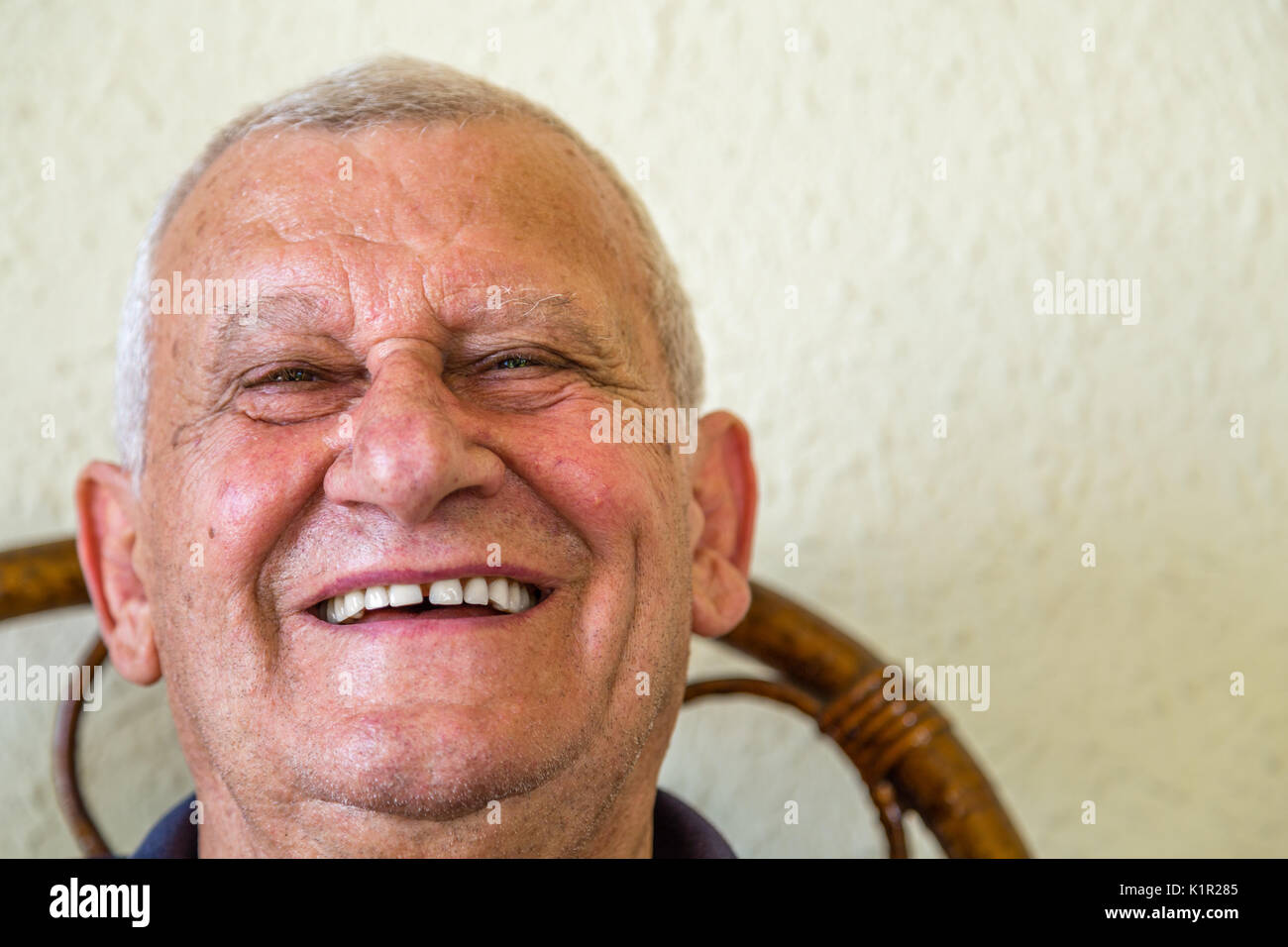 Anziani sorridenti mentre è seduto sulla sedia di vimini Foto Stock