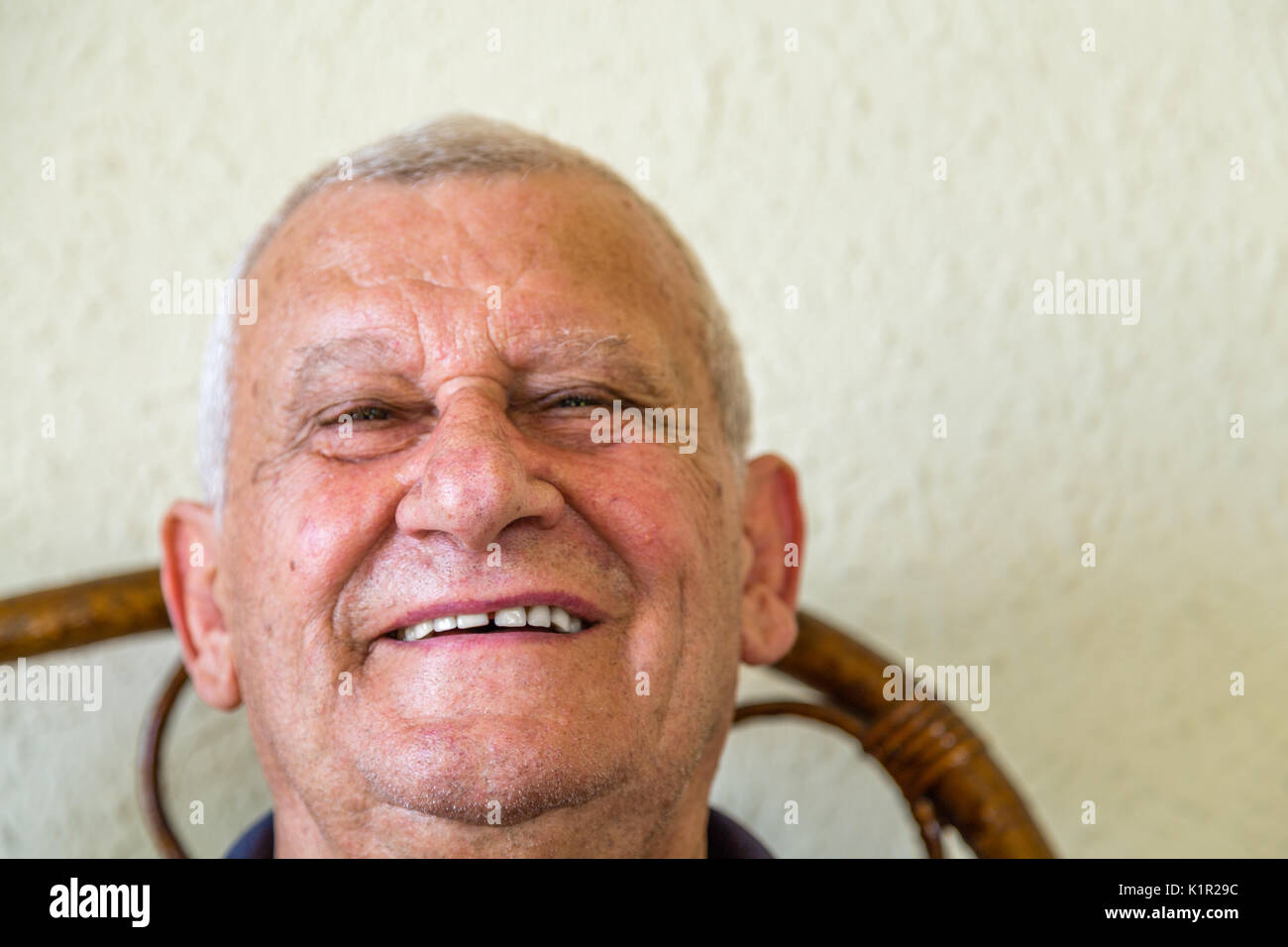 Anziani sorridenti mentre è seduto sulla sedia di vimini Foto Stock