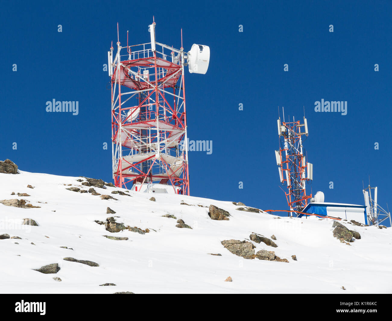 Un gruppo di antenne di comunicazione su una collina dalla giornata invernale con cielo blu in background. Foto Stock