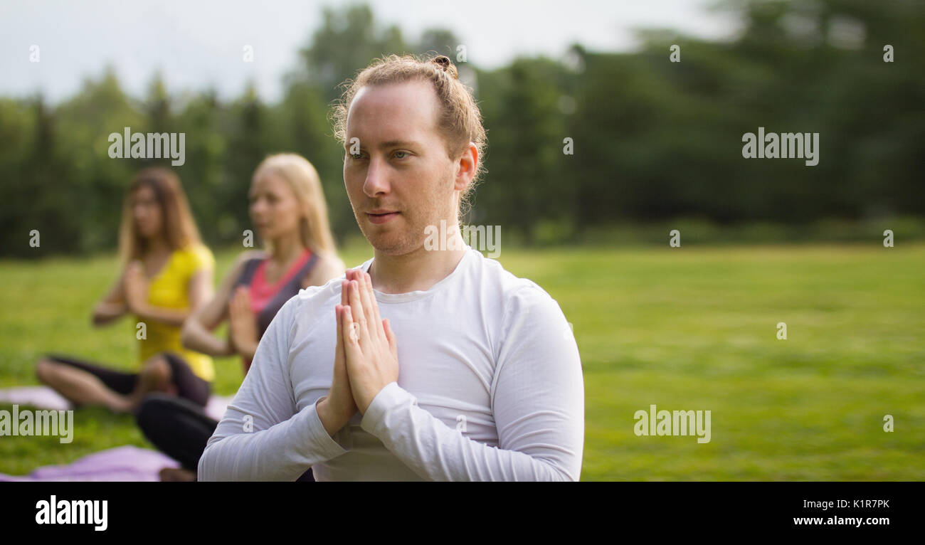 Lo Yoga sportivi nel parco - esegue esercizio all'aperto all'aperto al mattino Foto Stock