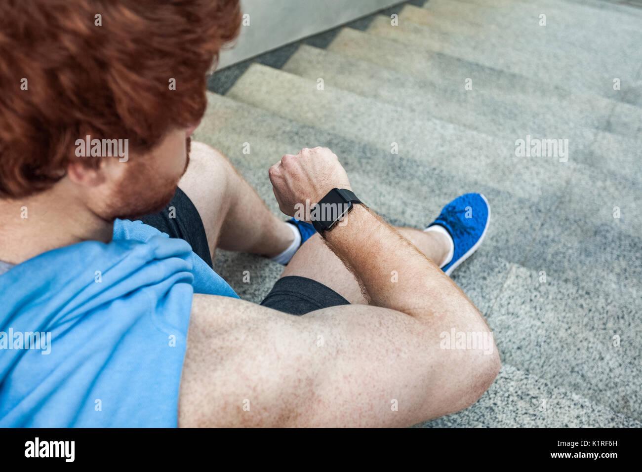 Vista da sopra. Atleta guardando smart watch e ritiene calorie dopo il duro allenamento. Colpo all'aperto. Estate Foto Stock