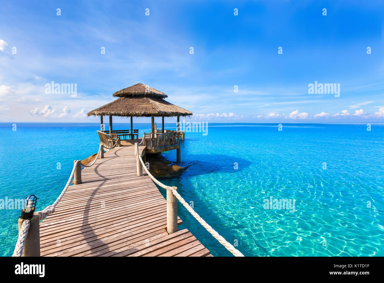 Bella estate tropicale spiaggia paesaggio, lussuoso hotel molo in legno trasparente con acqua del mare turchese Foto Stock