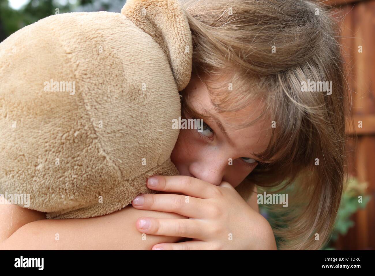 Close up ritratto di bambina holding orsacchiotto cercando intensa Foto Stock