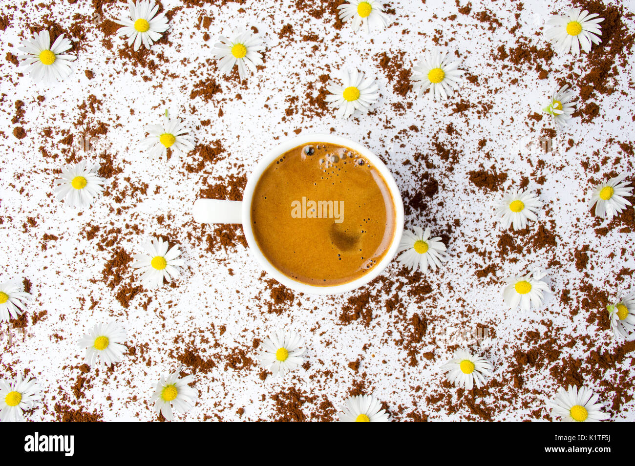 Tazza di caffè con i fiori di camomilla su bianco, laici piatta Foto Stock