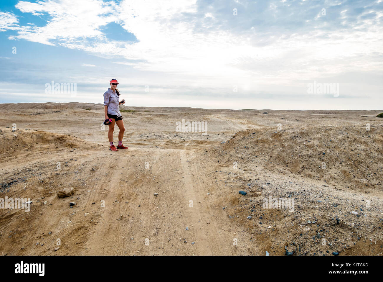 Femminile prendendo una pausa e sorridente alla fotocamera in un deserto in Perù. Foto Stock