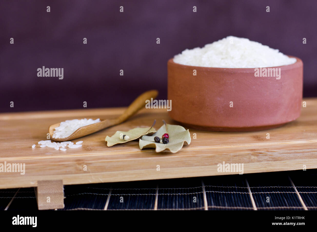 Riso in bianco in un vaso di argilla e il cucchiaio di legno. Foglie di alloro e il pepe nero. Foto Stock