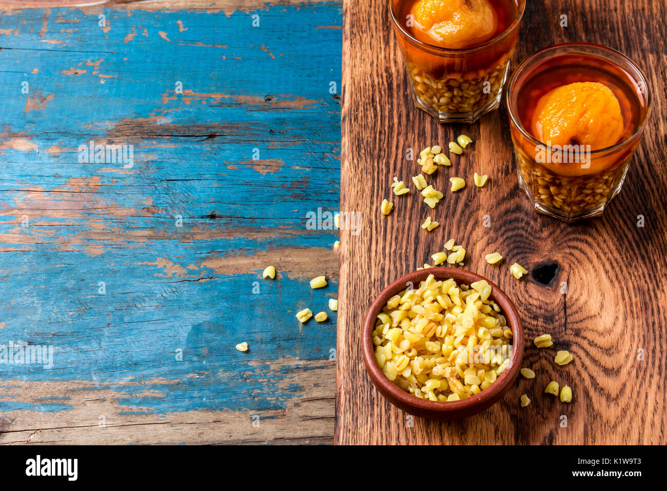 Mote con huesillo. Tradizionale bevanda cilena realizzato da cuocere il riso semigreggio e grano essiccato peach sulla tavola di legno, rustico sfondo blu. Foto Stock