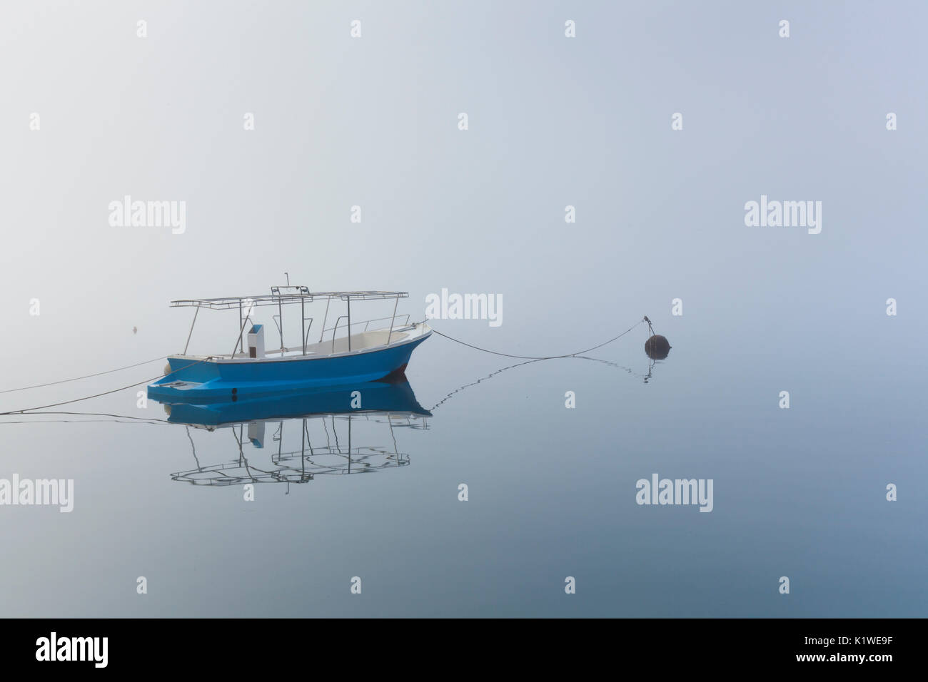 Una barca ancorata nel mare calmo della Baia di Kotor, Montenegro Foto Stock