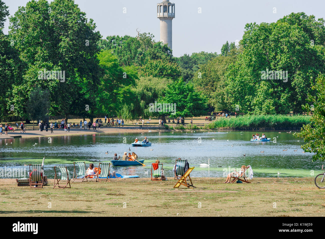 London Regent's Park, la vista del lago in barca e turisti che si godono un pomeriggio estivo con il minareto della moschea centrale nella parte posteriore, UK. Foto Stock
