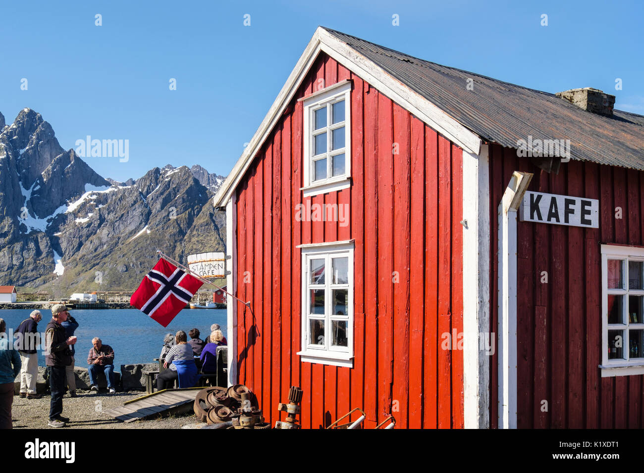 I turisti al di fuori Stampen Cafe in rosso edificio di legno in estate. Sund, Flakstadøya isola, isole Lofoten, Nordland, Norvegia e Scandinavia Foto Stock
