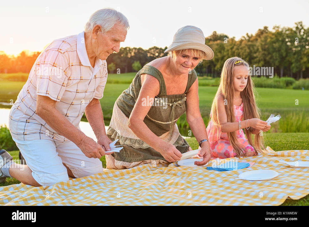 Personale senior con il nipote. Panno per picnic con piastre. Impostazione Picnic idee. Foto Stock