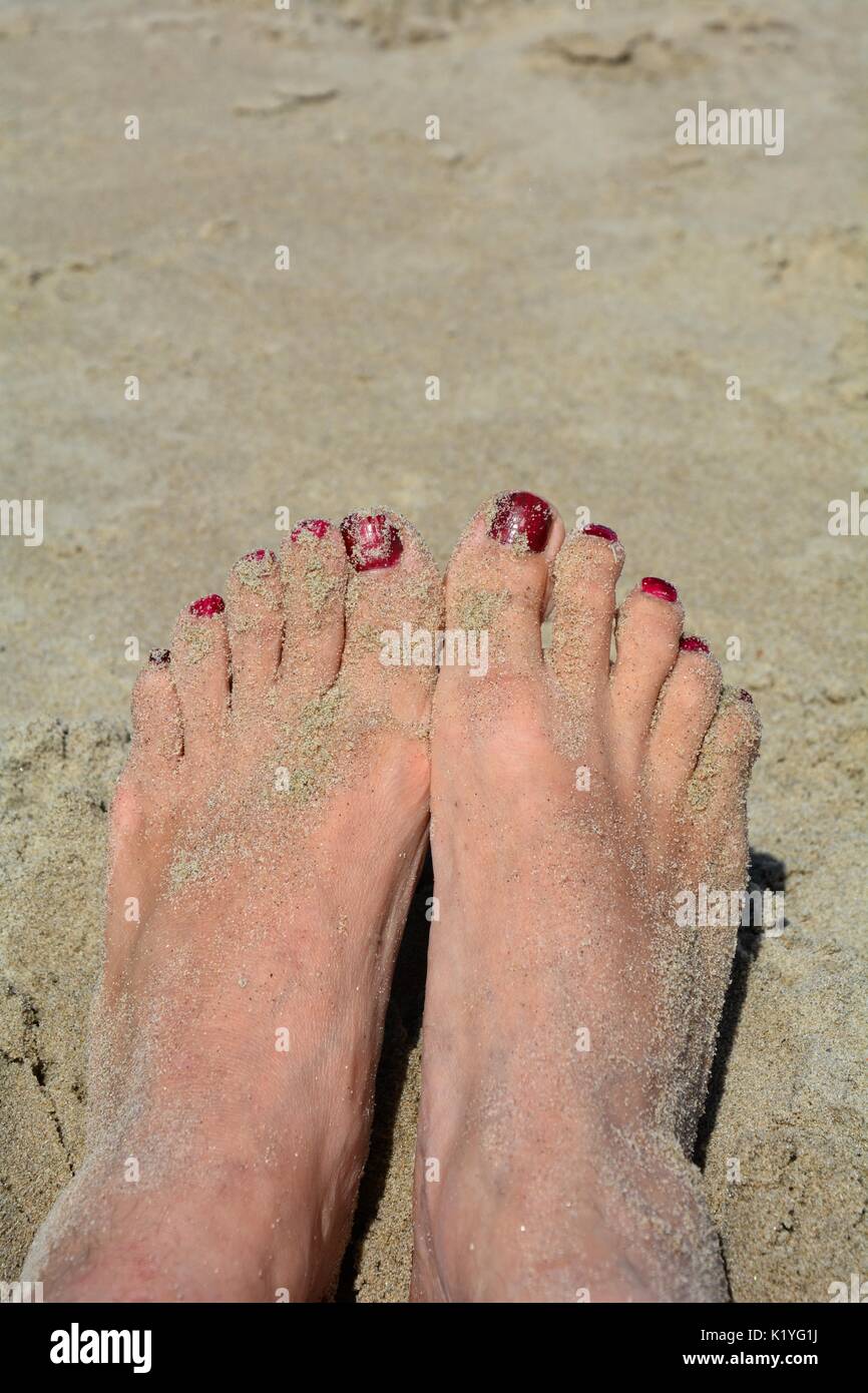 Piedi di sabbia con red toenails sulla spiaggia Foto Stock