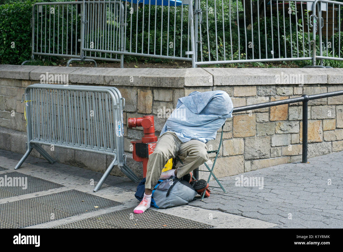 Un uomo non identificato, presumibilmente senzatetto, dormire durante la tarda mattinata in Union Square Park a Manhattan, New York City Foto Stock