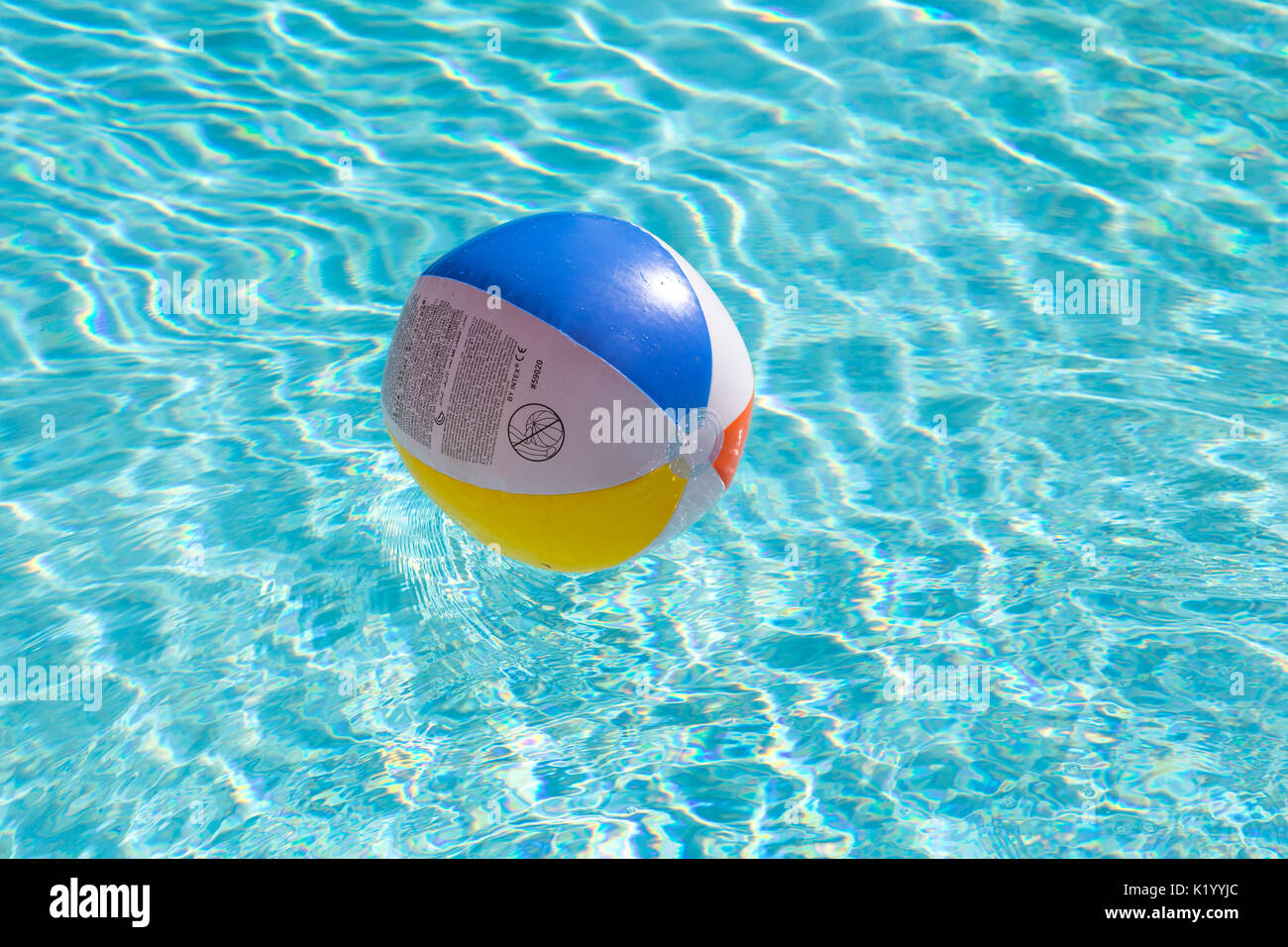 Palline da spiaggia colorate galleggiano in una bella piscina blu cristallo chiaro in una calda giornata estiva Foto Stock