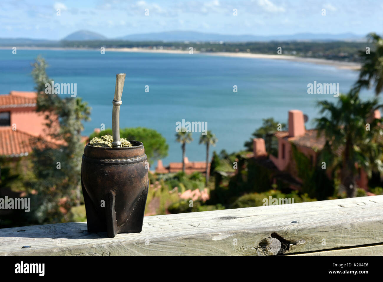 Tradizionale Calda Uruguay caffeina-bevanda ricca mate (yerba mate) in un Calabash Gourd con la vista mozzafiato dalle balene penisola (Punta Ballena) clo Foto Stock