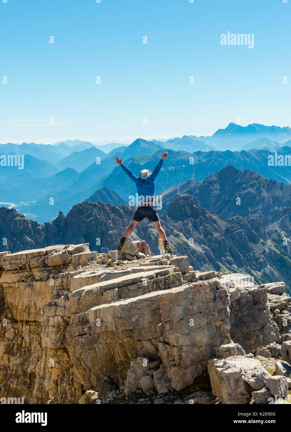 Escursionista bracci di estensione in aria, salto in aria, sulle montagne e sulle Alpi, il vertice del Hochvogel, Algovia, Algovia Alte Alpi, Bavaria Foto Stock