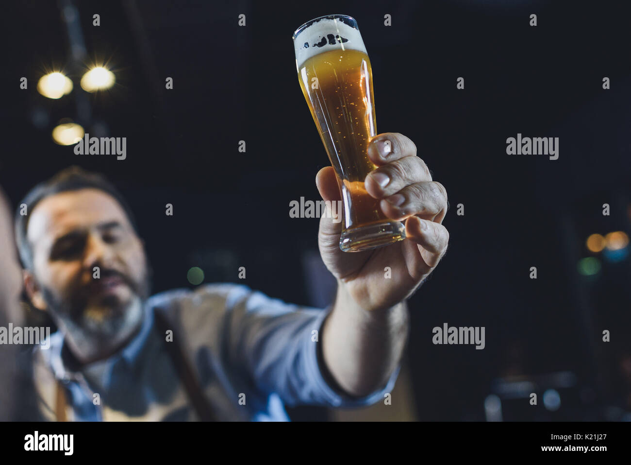 Birreria maschio lavoratore esaminando piccolo bicchiere di birra Foto Stock
