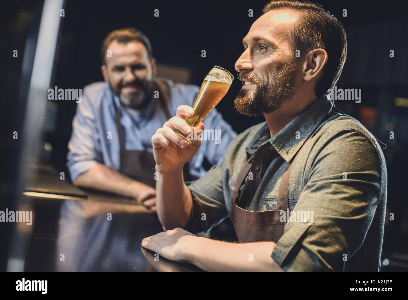 Birreria maschio lavoratore nel grembiule degustazione birra fresca Foto Stock