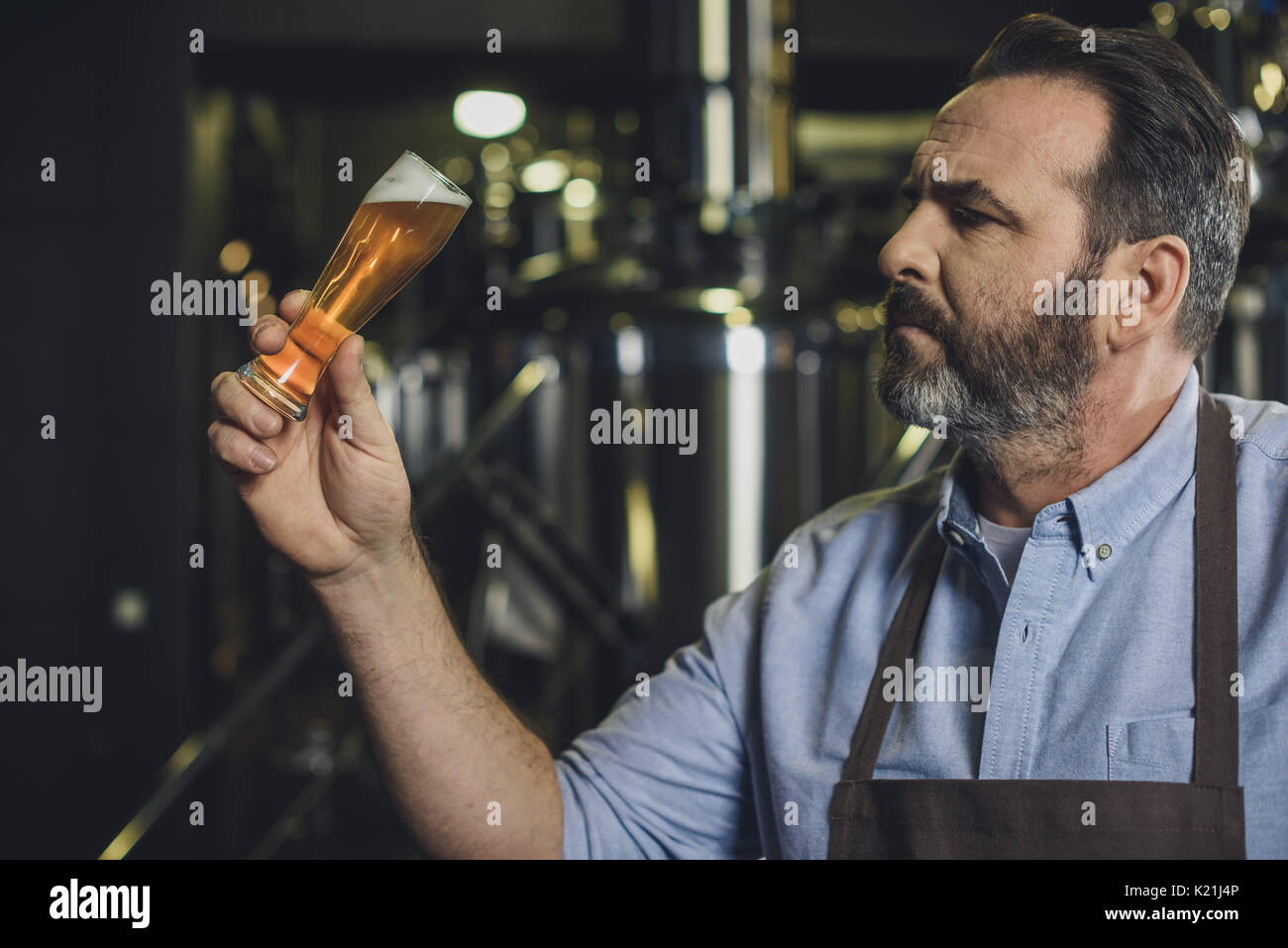 Birreria maschio lavoratore esaminando piccolo bicchiere di birra Foto Stock