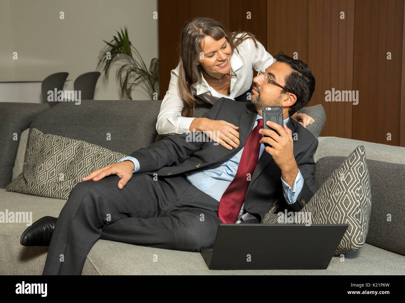 Uomo arabo lavorano a casa mentre la donna è guardando sopra la sua spalla cercando di ottenere la sua attenzione Foto Stock