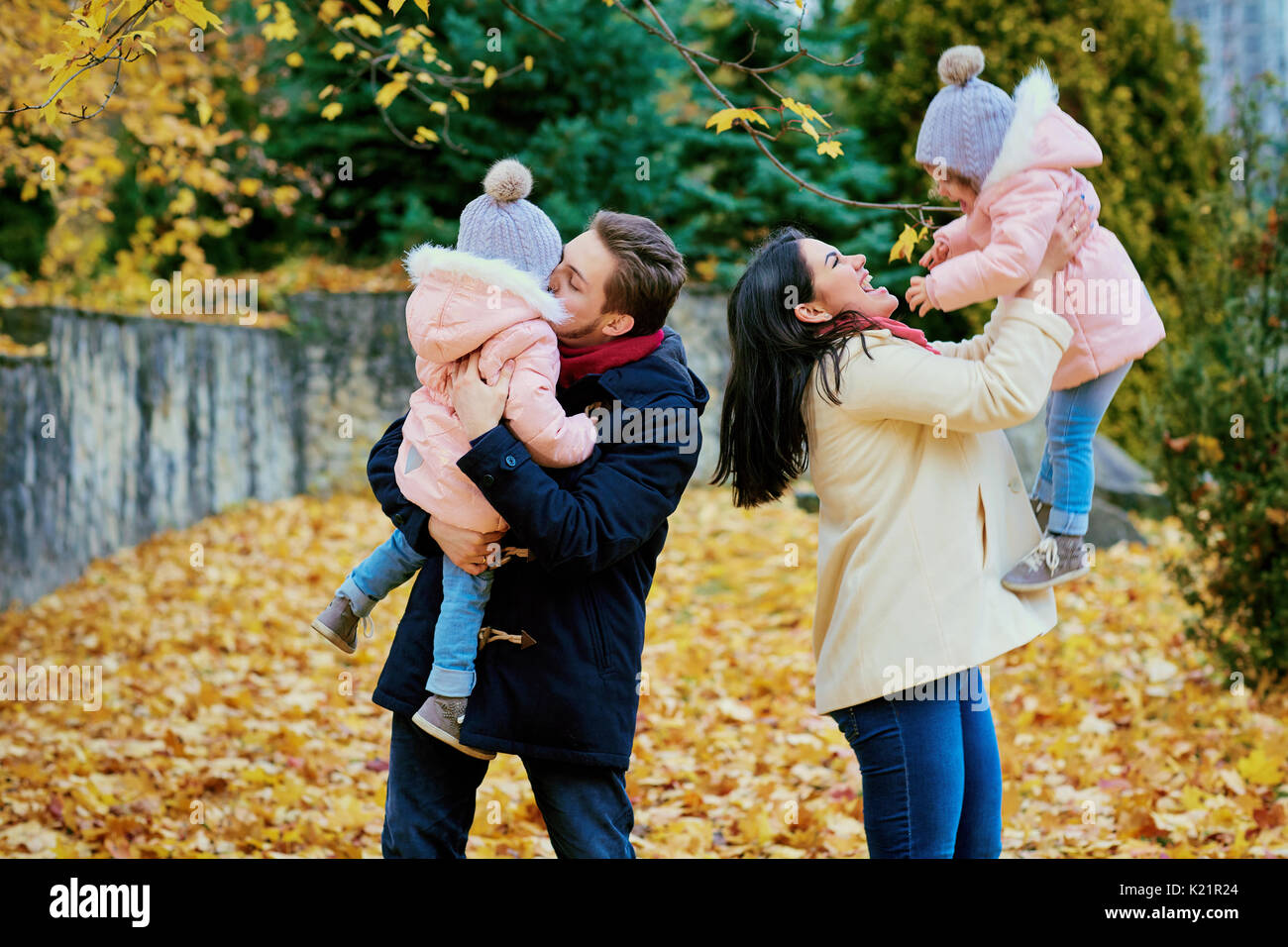 Genitori felici giocare con i bambini in un parco in autunno Foto Stock