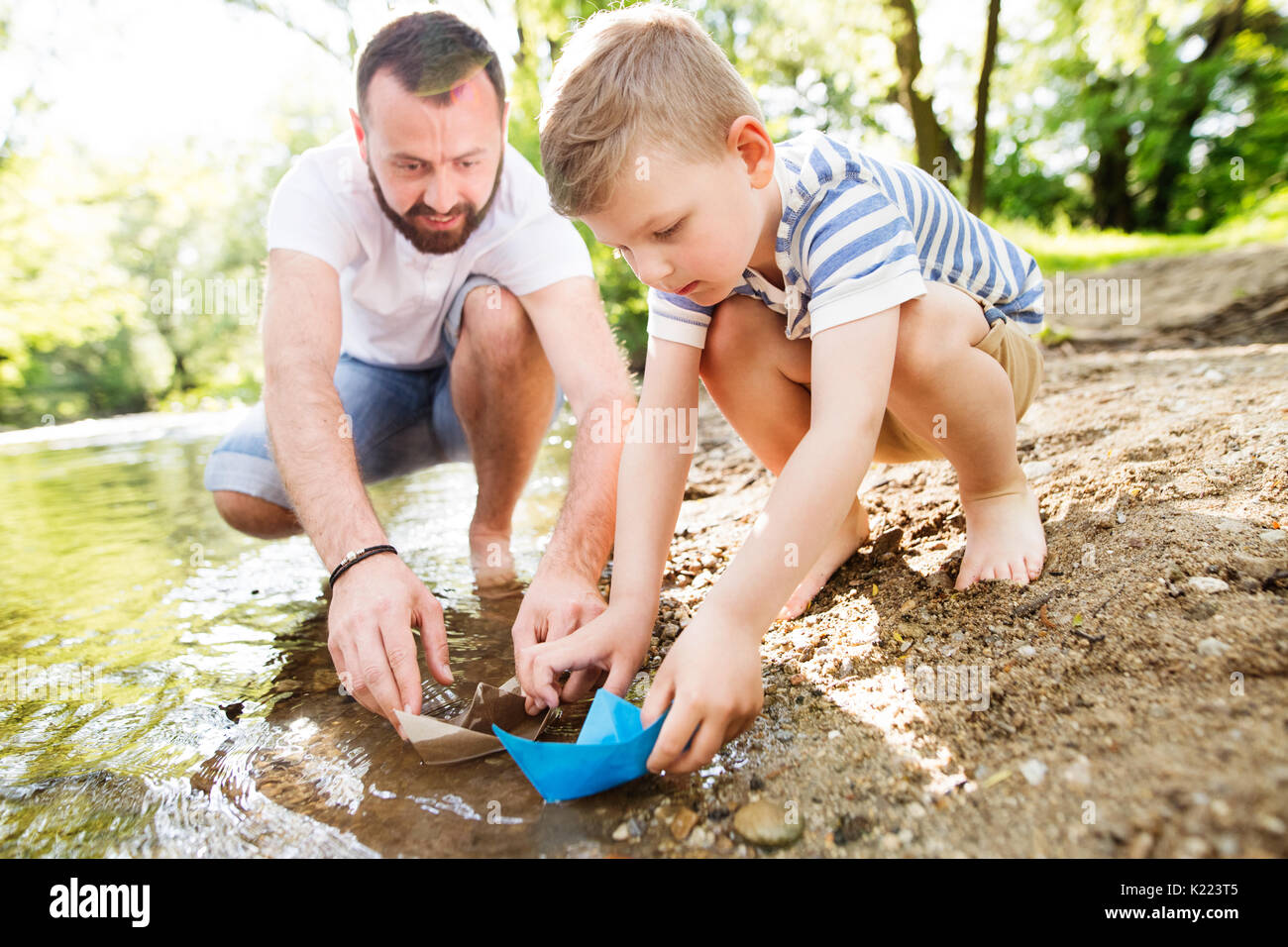 Giovane padre con little boy presso il fiume, soleggiata giornata di primavera. Foto Stock