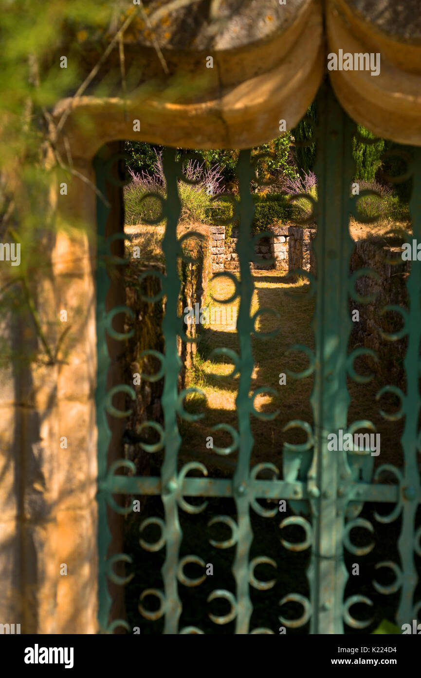 Giardino verde dietro la porta di metallo, Domme, Dordogna Foto Stock