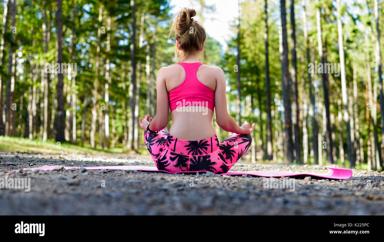 Giovane donna meditando nella posizione del loto la pratica dello yoga in una foresta. Concetto di libertà. Rilassatevi, il corpo e la mente la felicità. Foto Stock