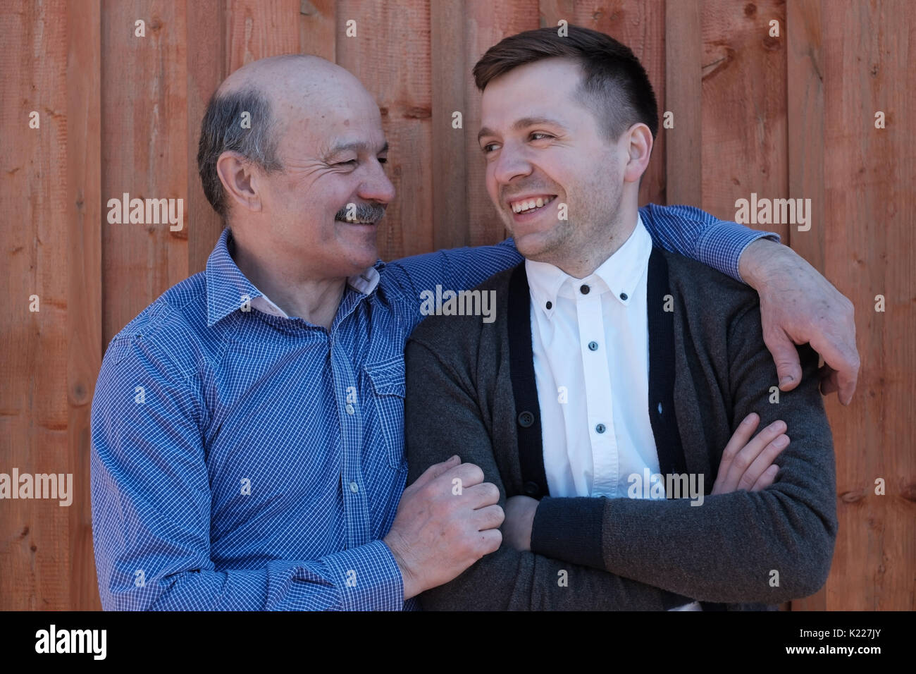 Padre e figlio guardando ogni altro su sfondo di legno. Foto Stock