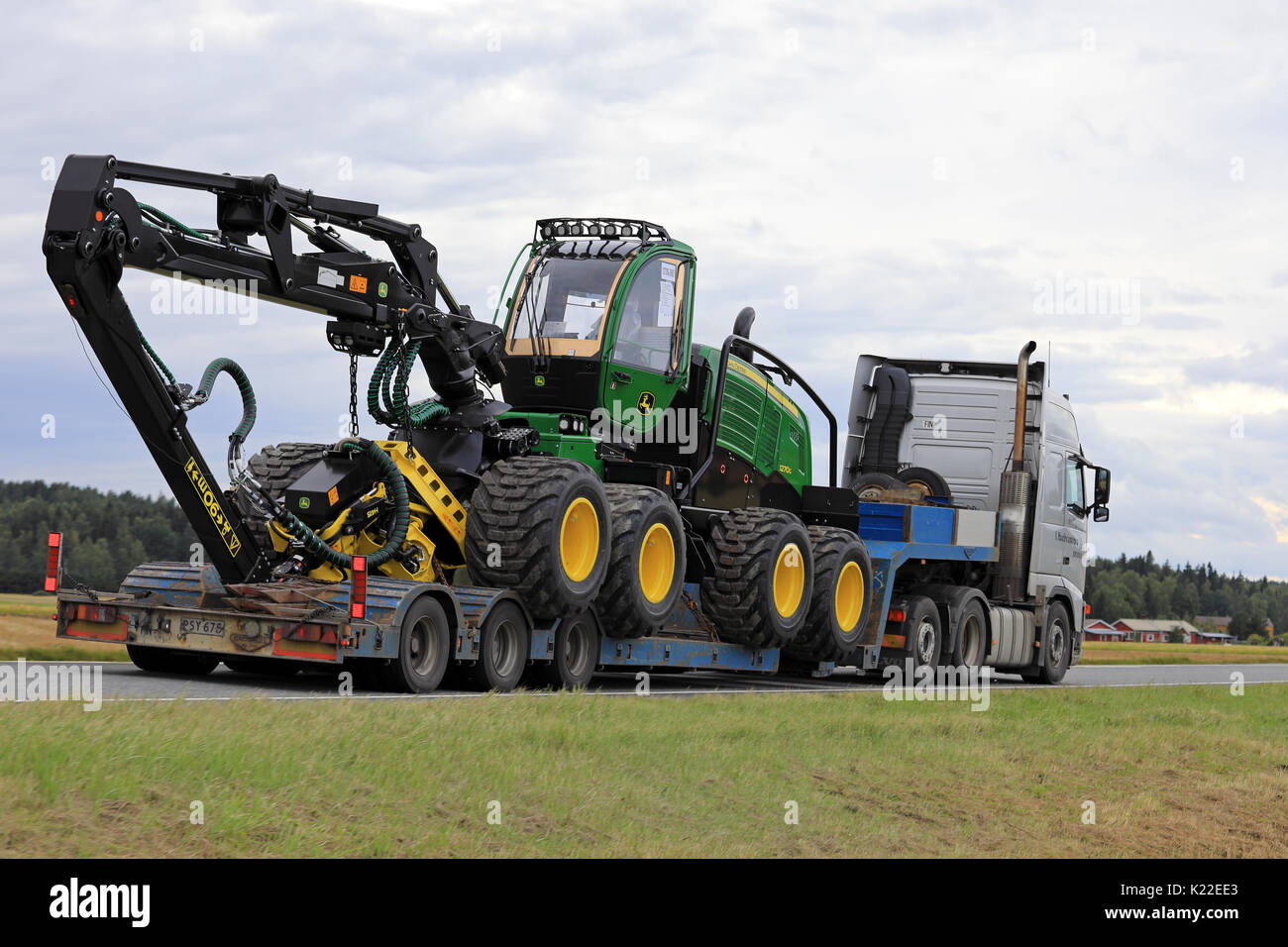 JOKIOINEN, Finlandia - 25 agosto 2017: vista posteriore di Volvo FH12 semi rimorchio trasporto di John Deere 1270 G gommati Trincia forestale a velocità su strada Foto Stock