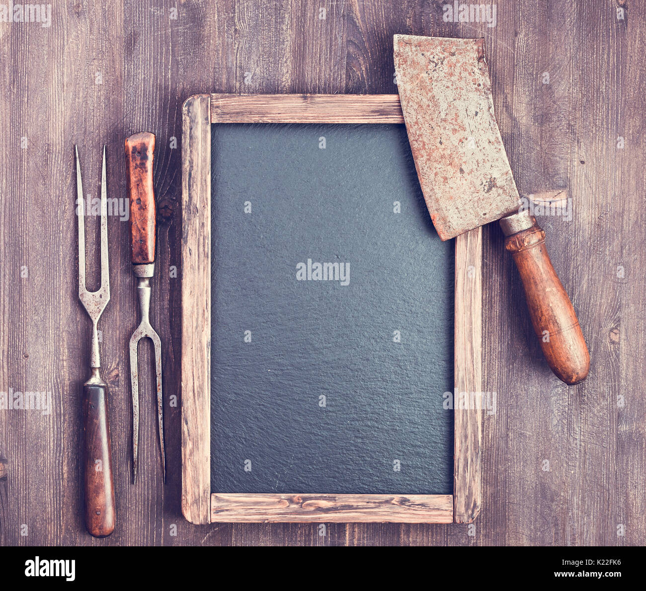Rustico menu vuoto lavagna con forche e carne cleaver su sfondo di legno con spazio di copia Foto Stock