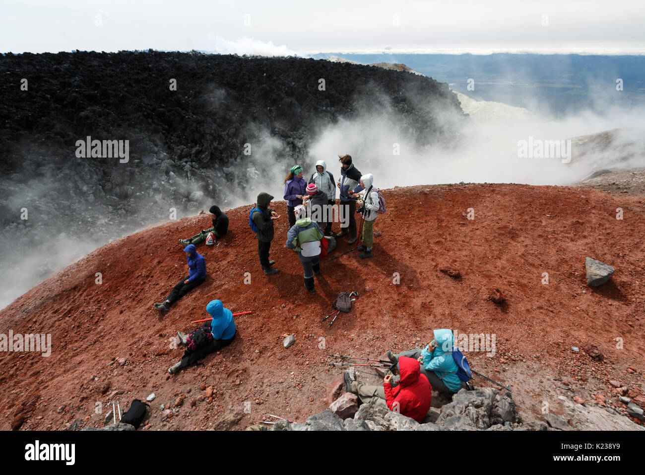 Un folto gruppo di turisti e viaggiatori riposa nel cratere attivo del vulcano Avachinsky dopo ore di scalata alla cima del vulcano su Kamchatka. Foto Stock