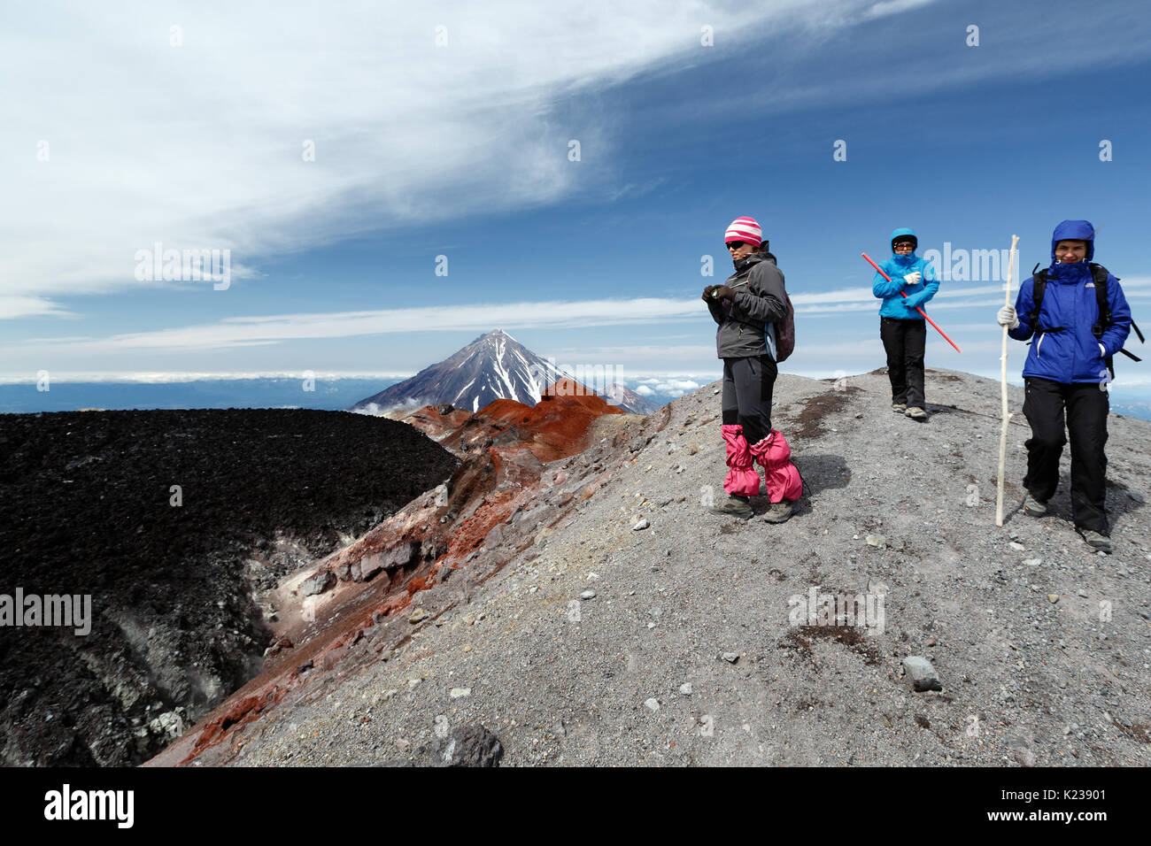 Tre donne giovani turisti passeggiate in montagna sentiero escursionistico sul cratere sommitale del attivo vulcano Avachinsky sulla penisola di Kamchatka. Foto Stock