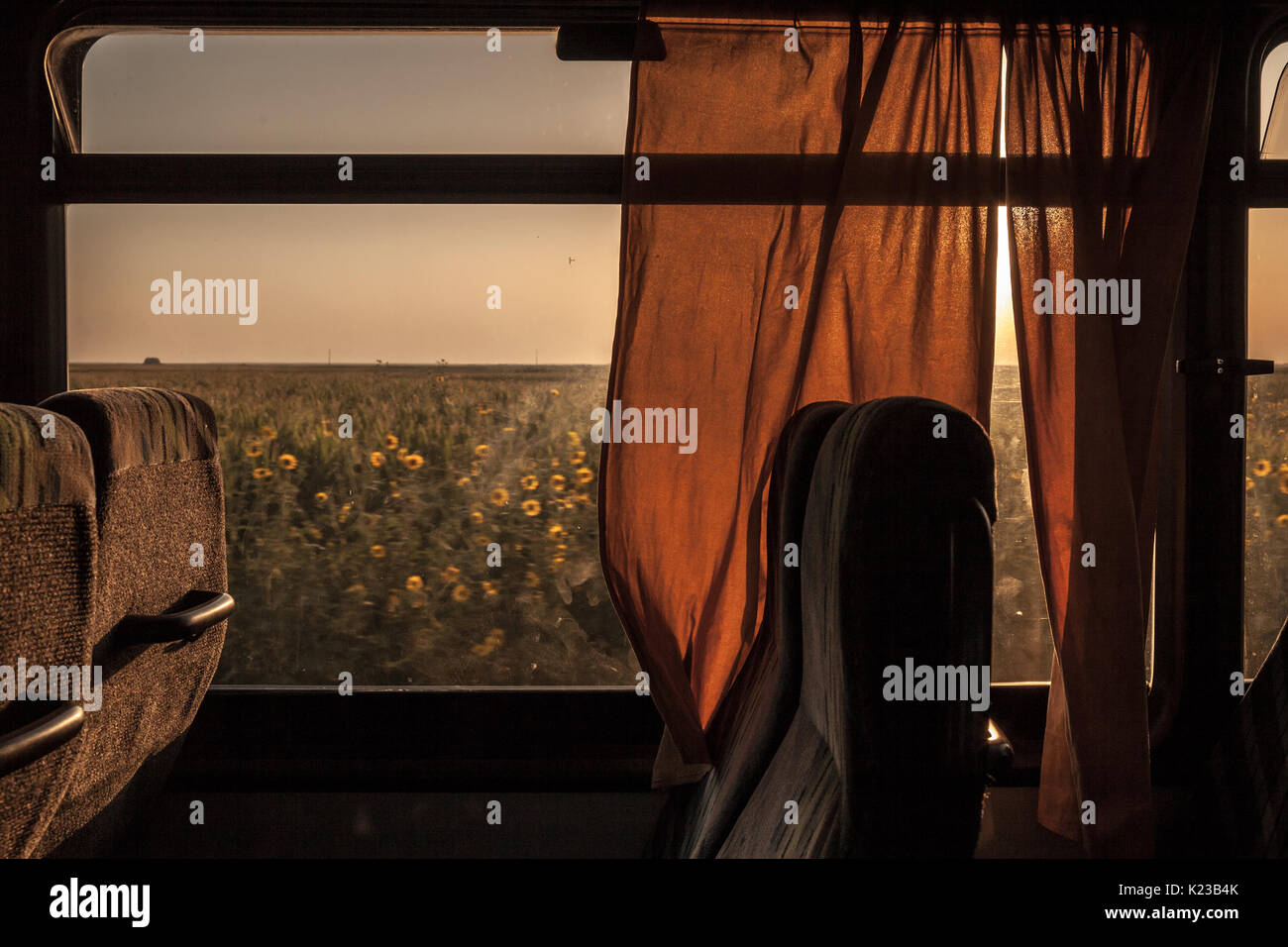 Vuoto sedile dell'autobus preso in un vecchio autobus vintage durante il tramonto, un campo può essere visto nell'immagine di sfondo di un vuoto in poltrona prese durante un journ Foto Stock