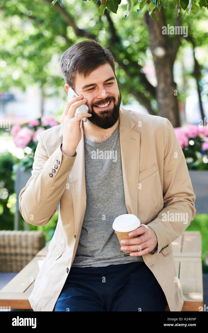L uomo moderno godendo di conversazione telefonica all'aperto Foto Stock