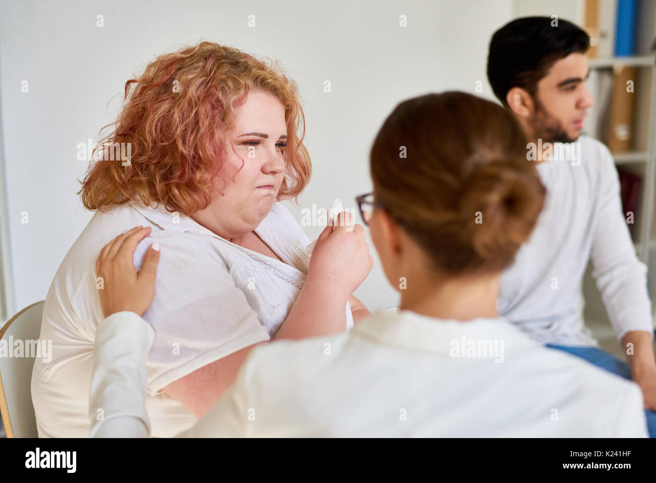 Obesi giovane donna che piange a sostegno sessione di gruppo Foto Stock