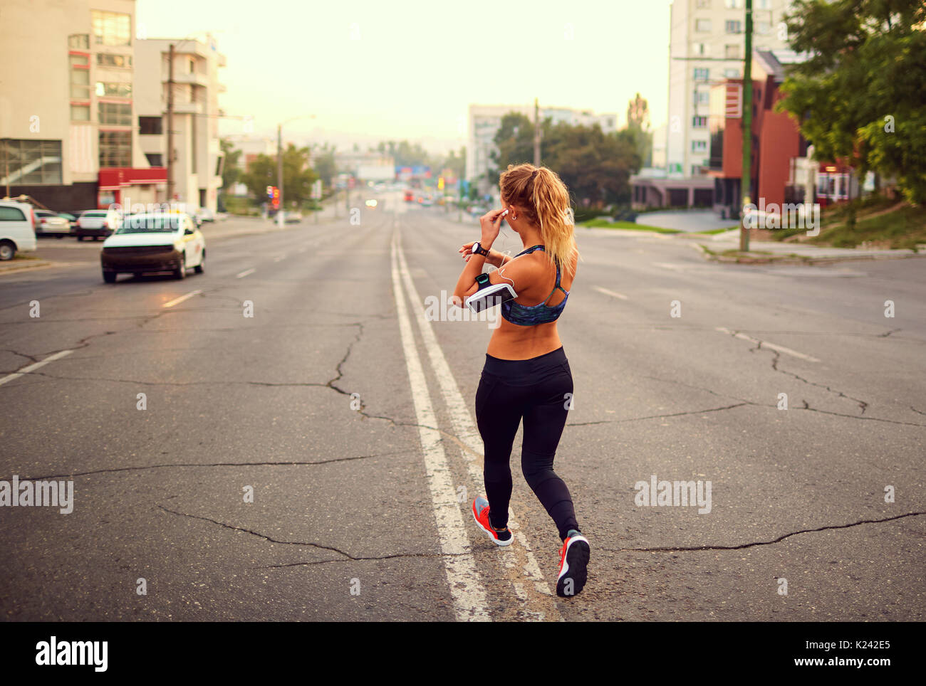 La ragazza runner corre lungo le strade della città jogging Foto Stock
