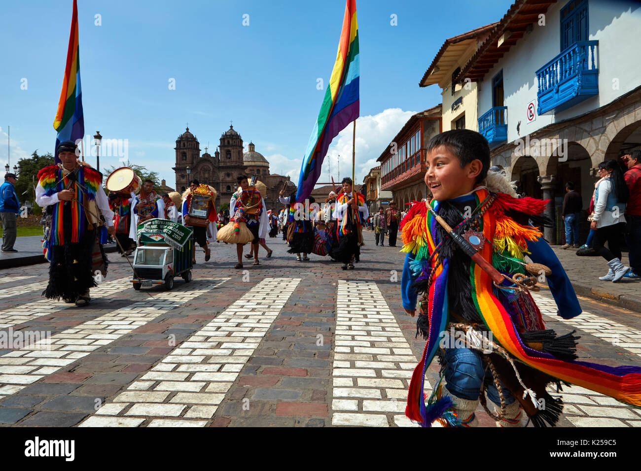 Piccolo ragazzo in costume indigeno in parata e bandiere arcobaleno di Cusco, Plaza de Armas, Cusco, Perù, Sud America Foto Stock