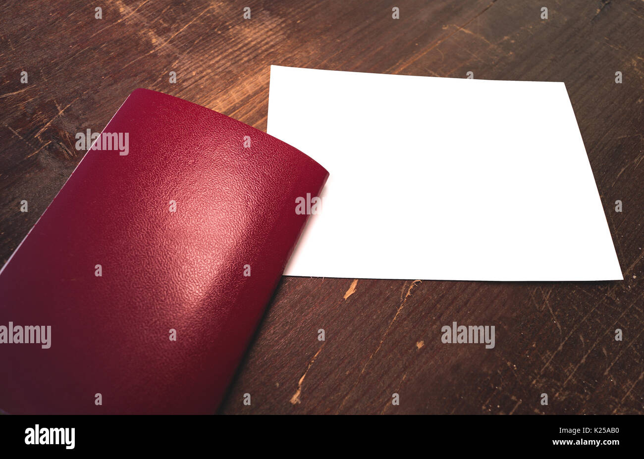 Vuoto passaporto rosso e di un bianco vuoto post scheda su un sfondo di legno Foto Stock