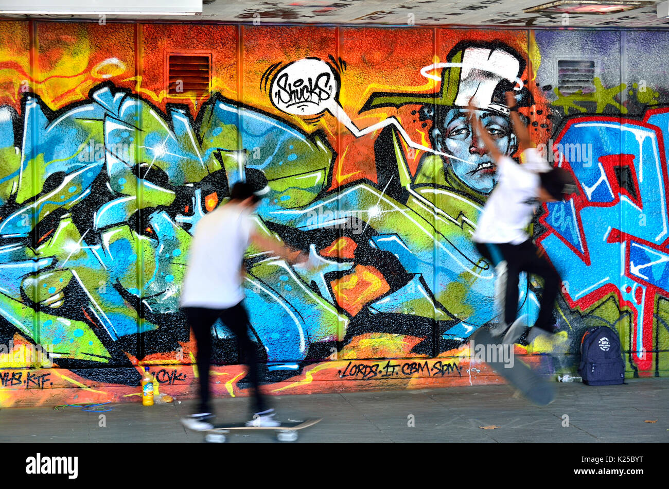 Londra, Inghilterra, Regno Unito. Lo skateboard nella Southbank Undercroft, sotto il Teatro Nazionale. Graffiti e un guidatore di skateboard (composito di due immagini) Foto Stock