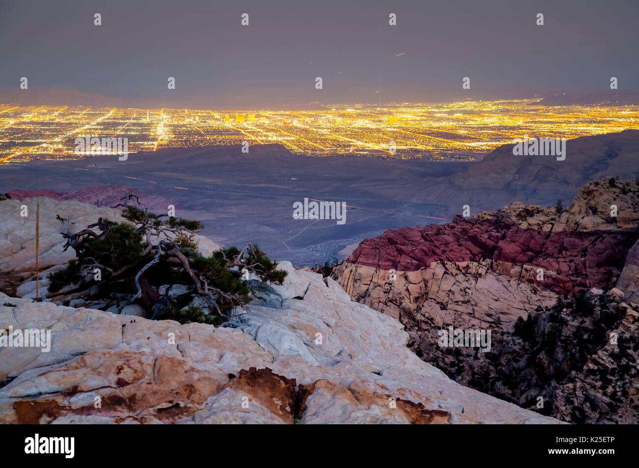 Red formazioni rocciose presso il Red Rock Canyon National Conservation Area con le luci di Las Vegas nella distanza 26 Settembre 2016 vicino a Las Vegas, Nevada. Foto Stock