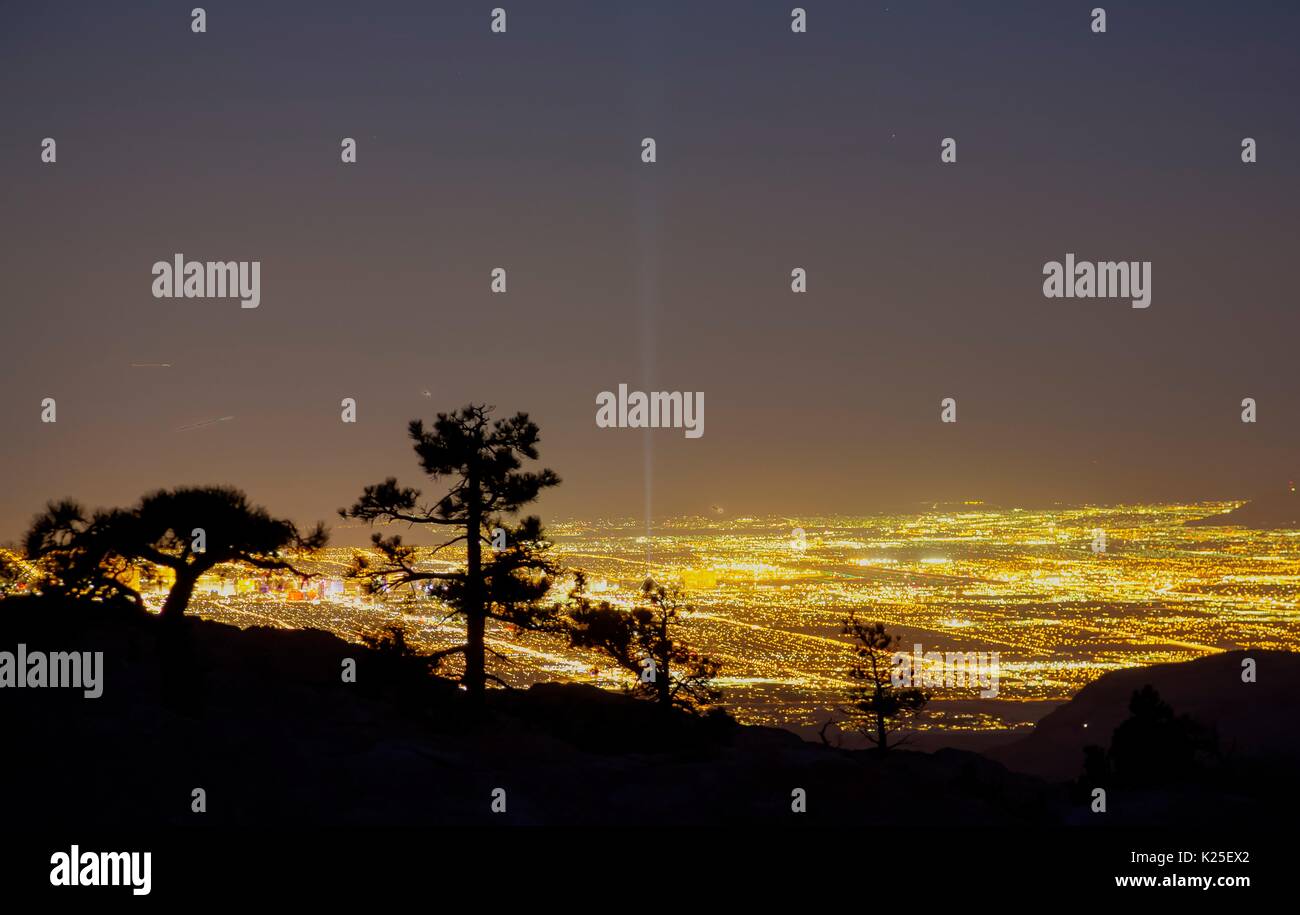 Il sole scende oltre le formazioni rocciose presso il Red Rock Canyon National Conservation Area con stagliano pinyon alberi di pino e dalle luci di Las Vegas nella distanza 26 Settembre 2016 vicino a Las Vegas, Nevada. Foto Stock
